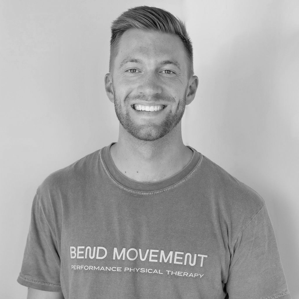 A man with a beard is smiling in a black and white photo.