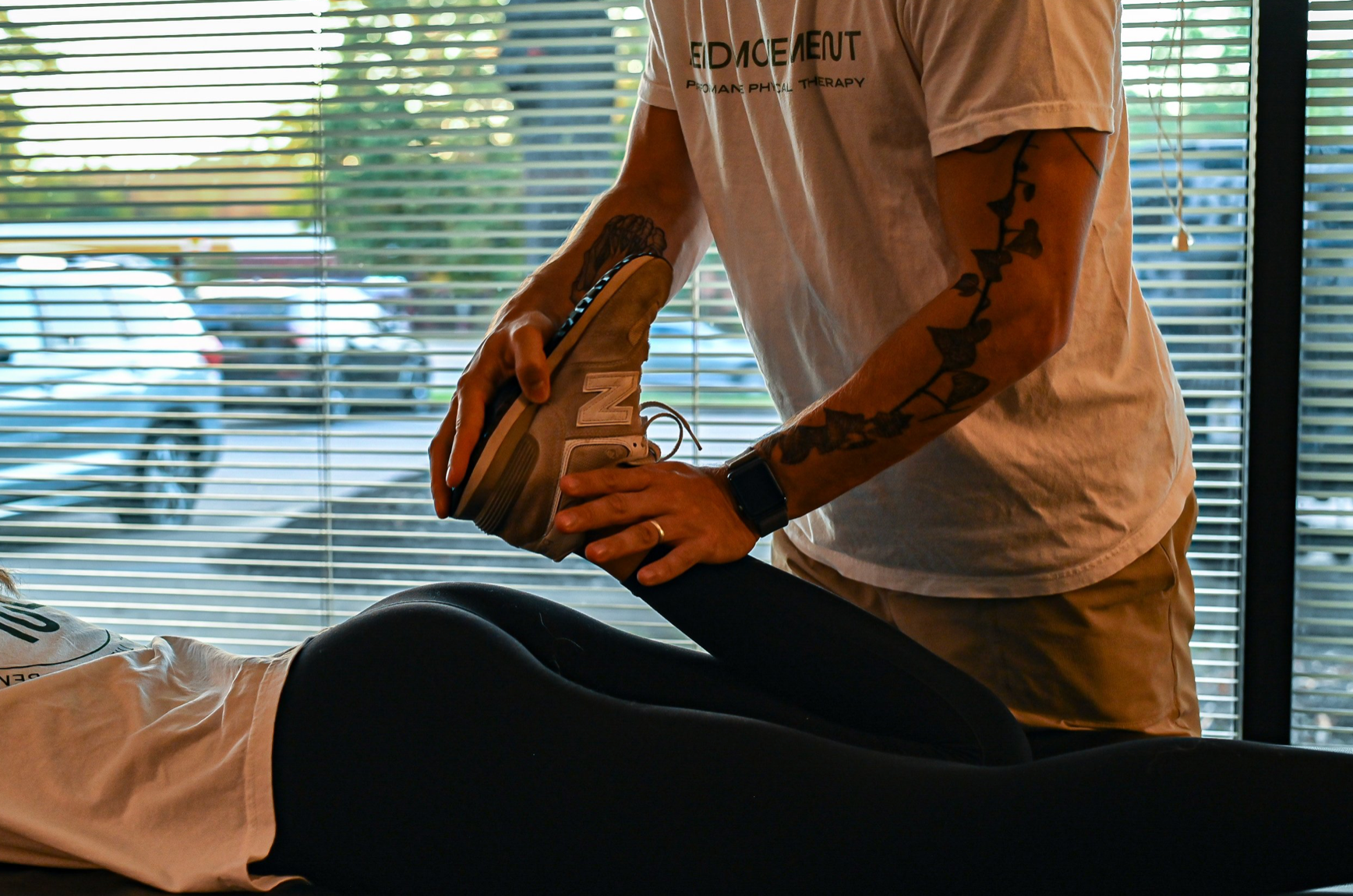 A man is stretching a woman 's leg on a table.