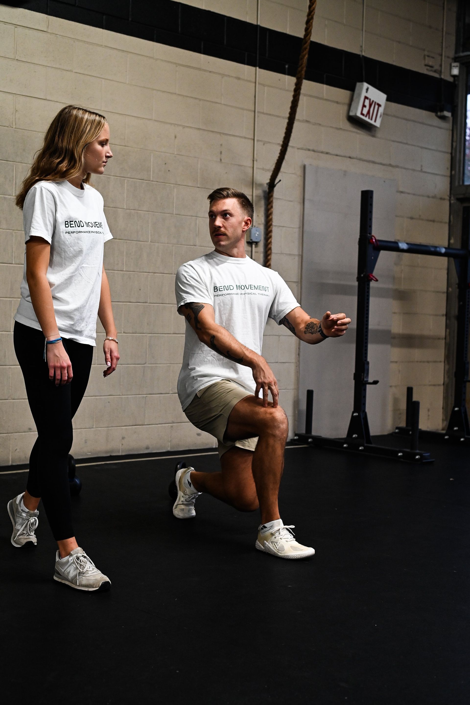 A man and a woman are doing squats in a gym.