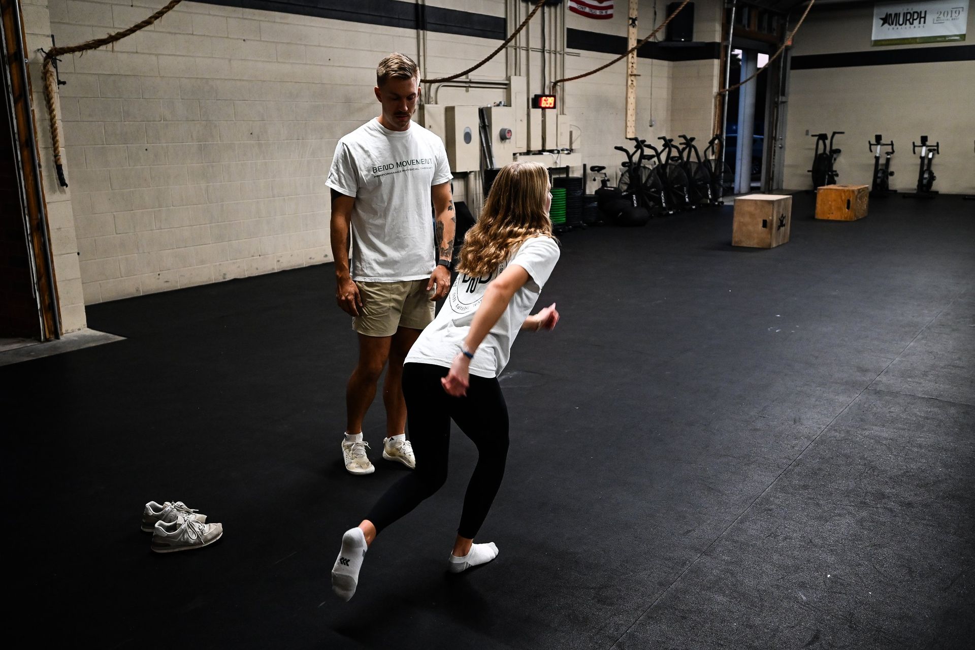 A man and a woman are standing in a gym.