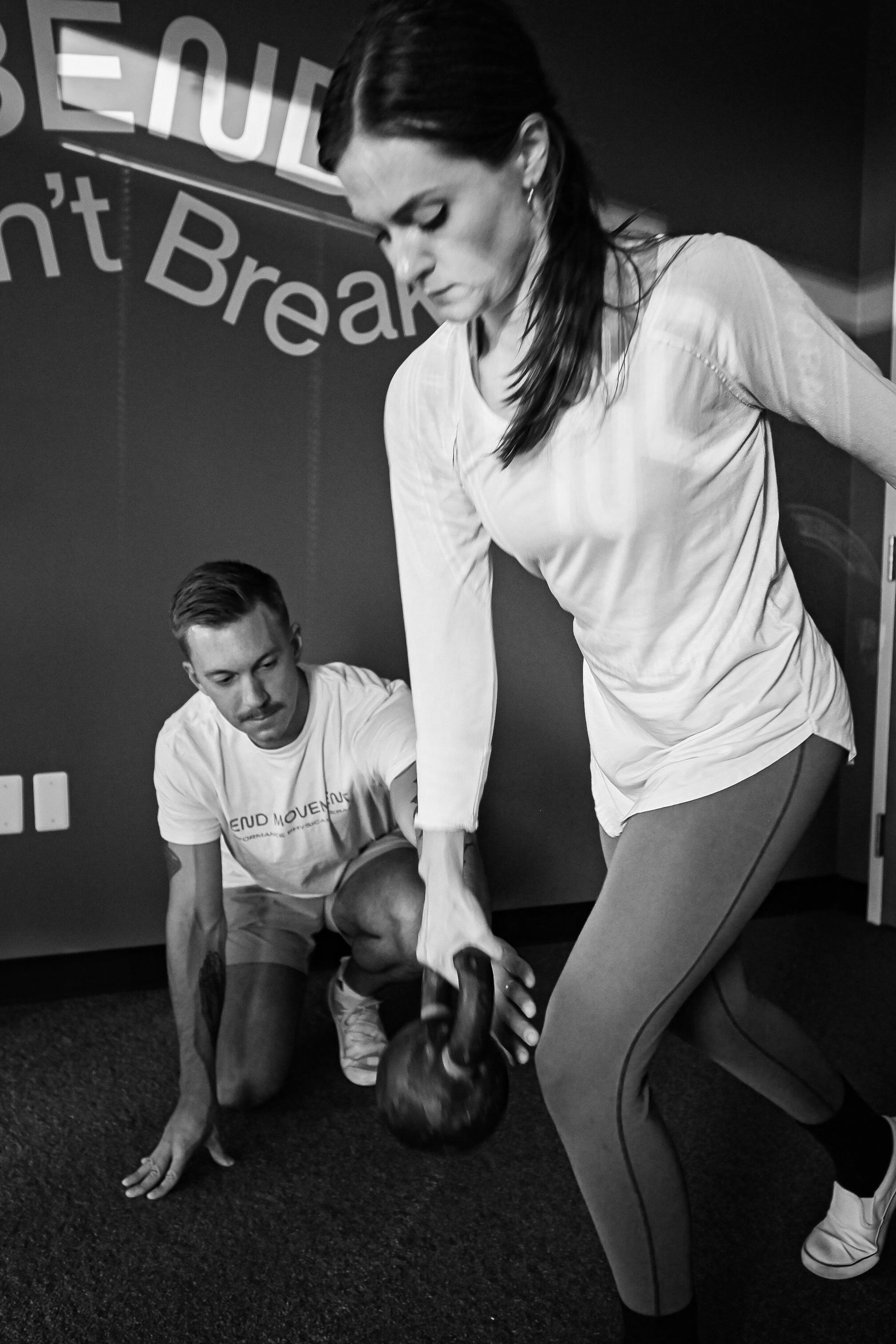 A black and white photo of a woman holding a kettlebell