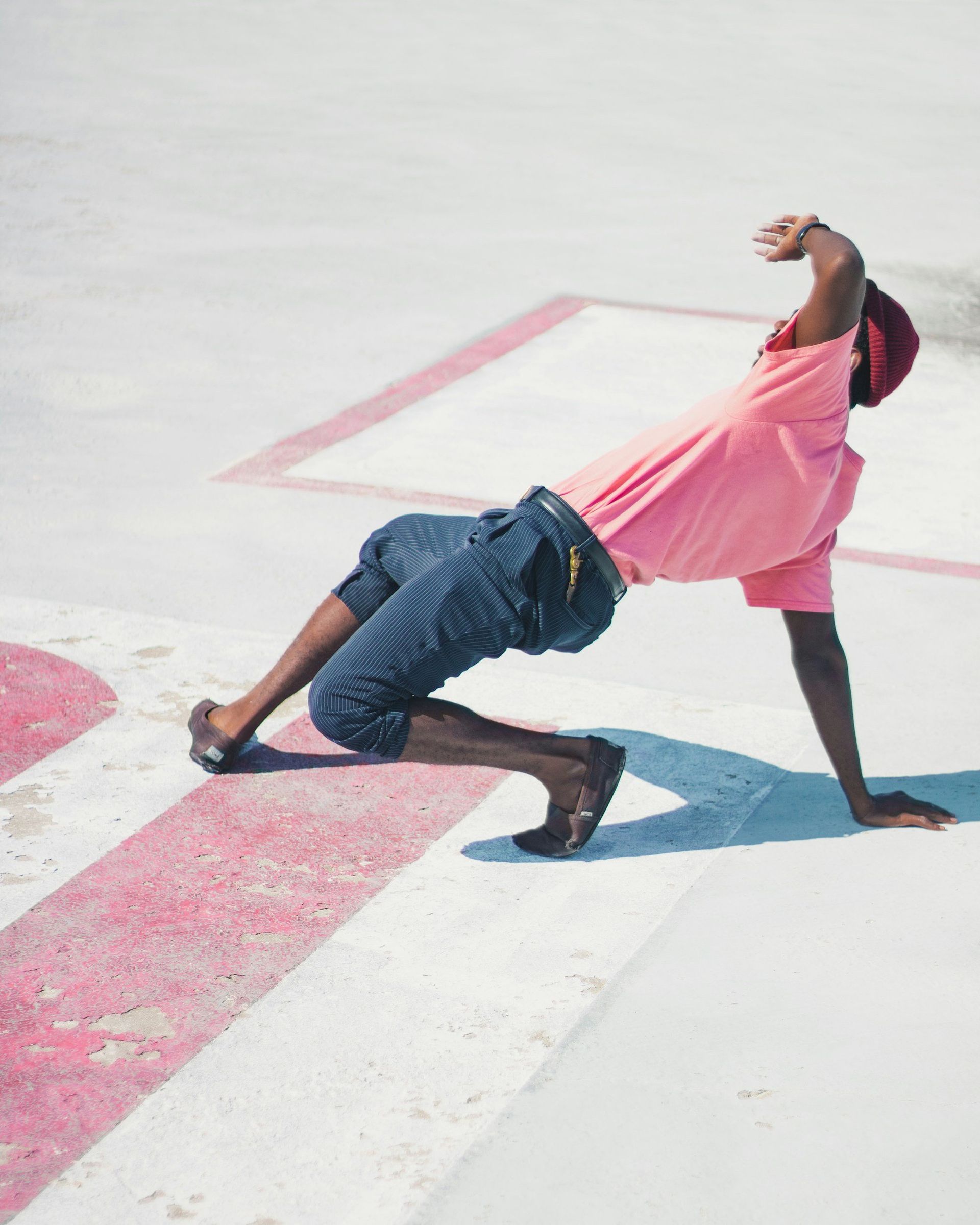 A man in a pink shirt is doing a handstand on the ground.