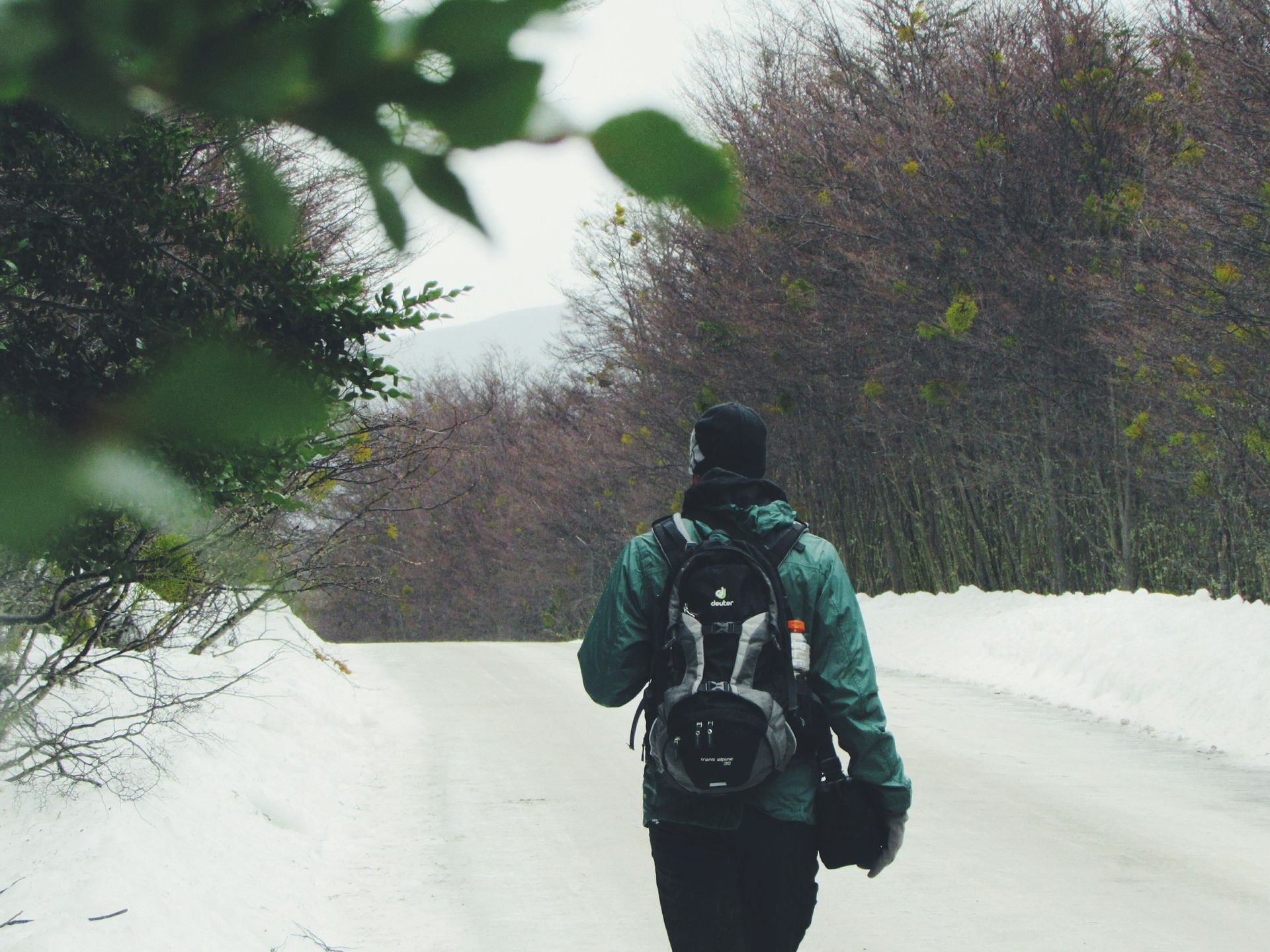 A person with a backpack is walking down a snowy road