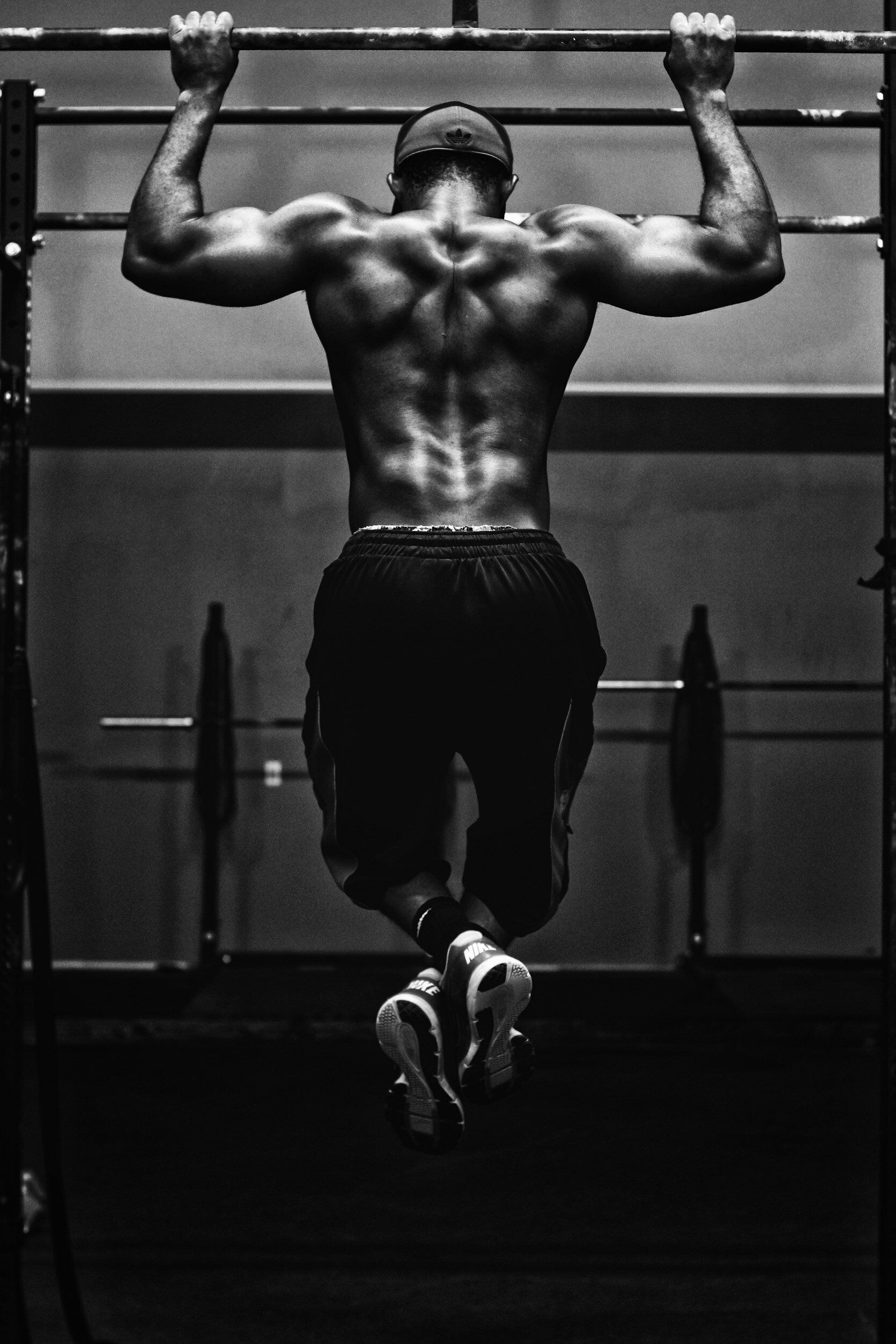 A man is doing pull ups on a bar in a gym.