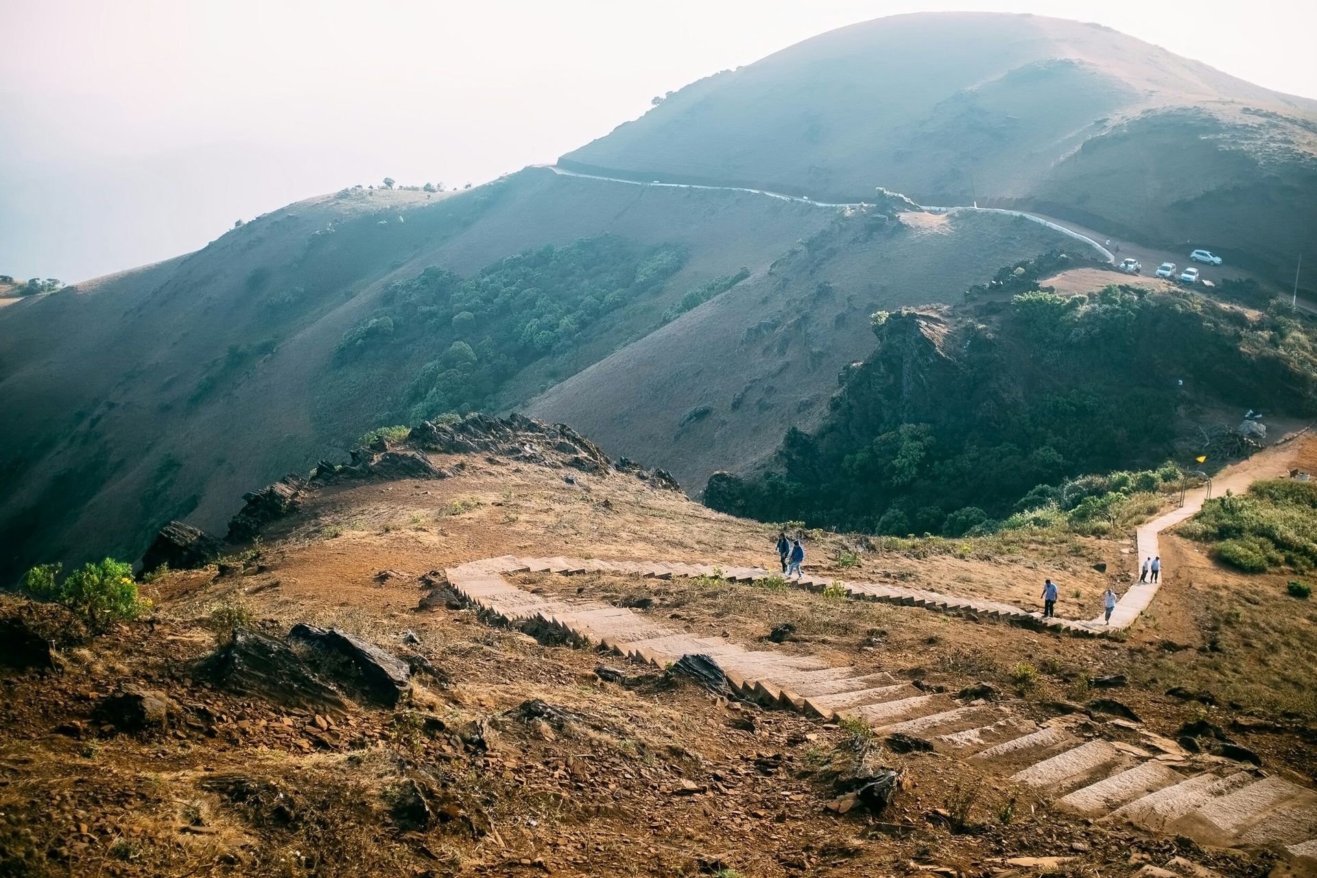 A group of people are walking down a dirt path on top of a hill.