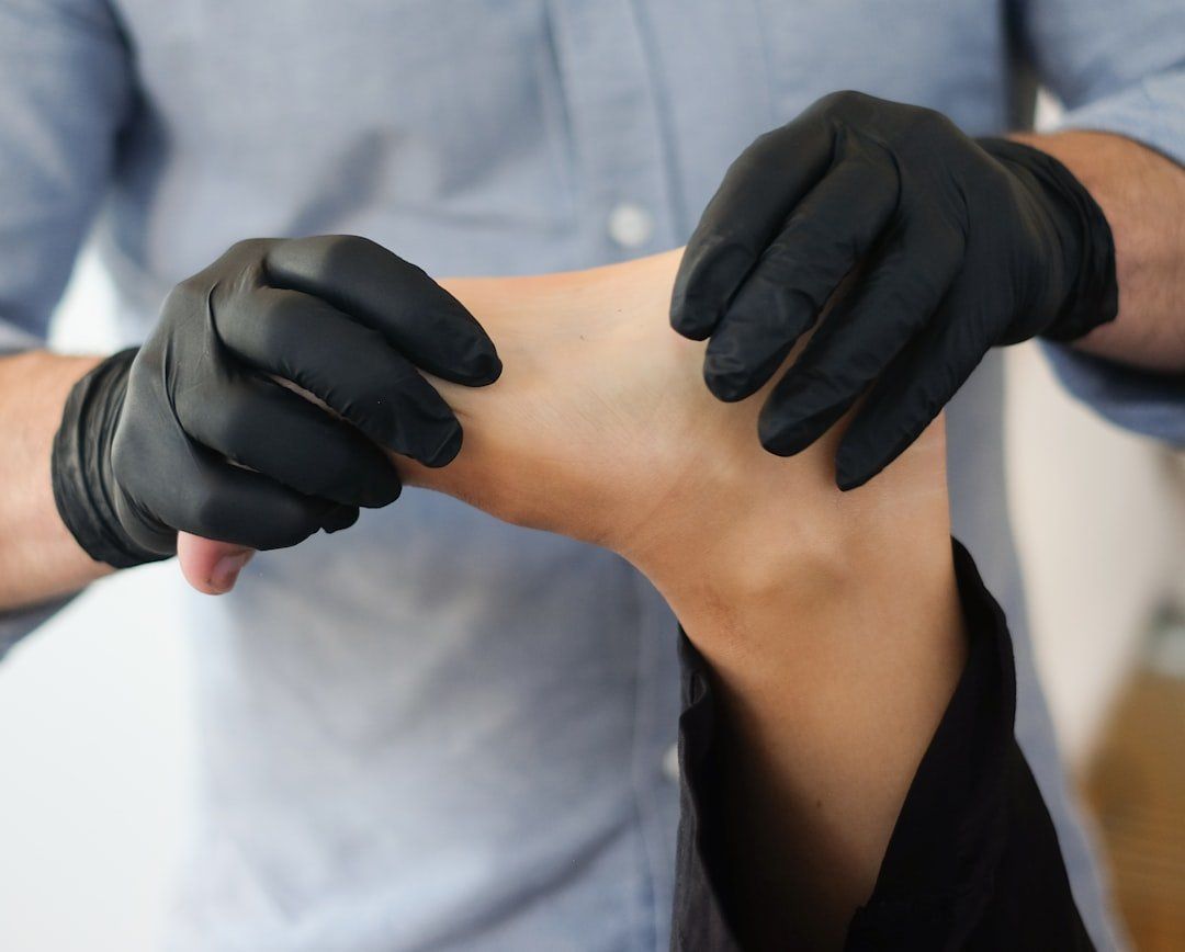 A person wearing black gloves is examining another person 's foot