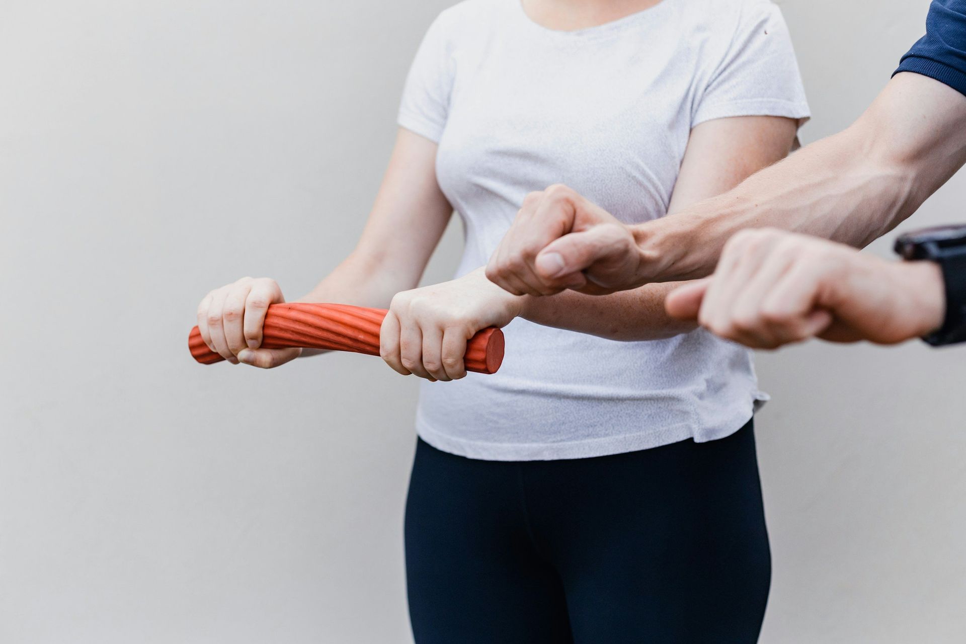 A man and a woman are holding a red stick in their hands.
