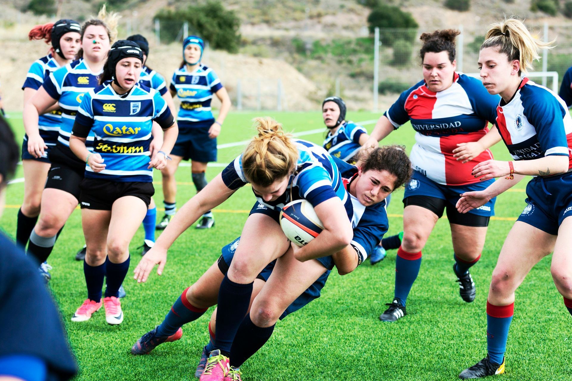 A group of women are playing rugby on a field.