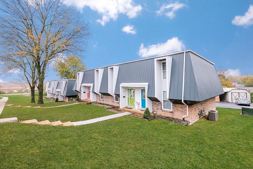 A row of apartment buildings with a lush green lawn in front of them.