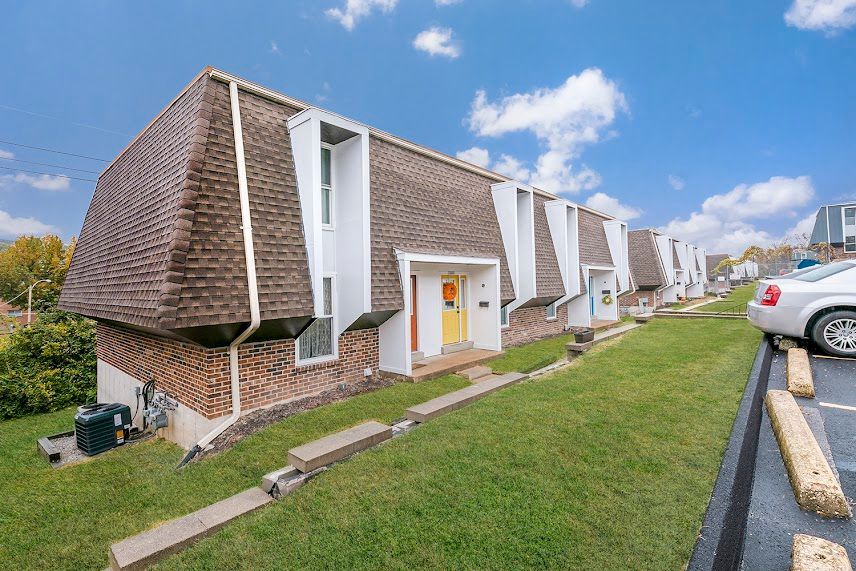 A row of apartment buildings with cars parked in front of them.