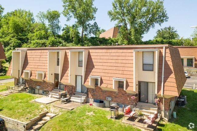 An aerial view of a brick apartment building with a lush green lawn in front of it.