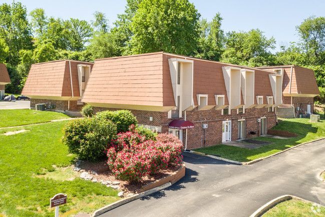 An aerial view of a row of apartment buildings surrounded by trees and grass.