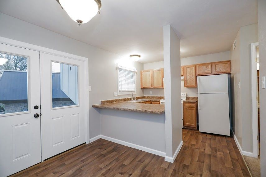 A kitchen with a refrigerator , cabinets , and hardwood floors.