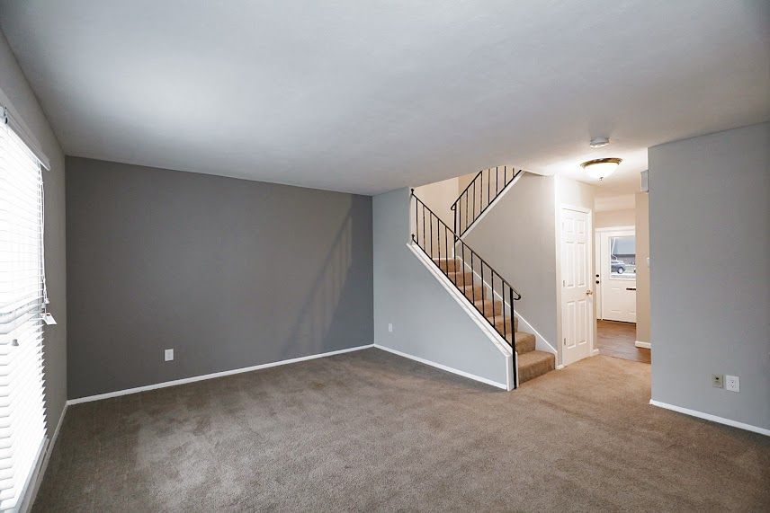 An empty living room with stairs leading up to the second floor.