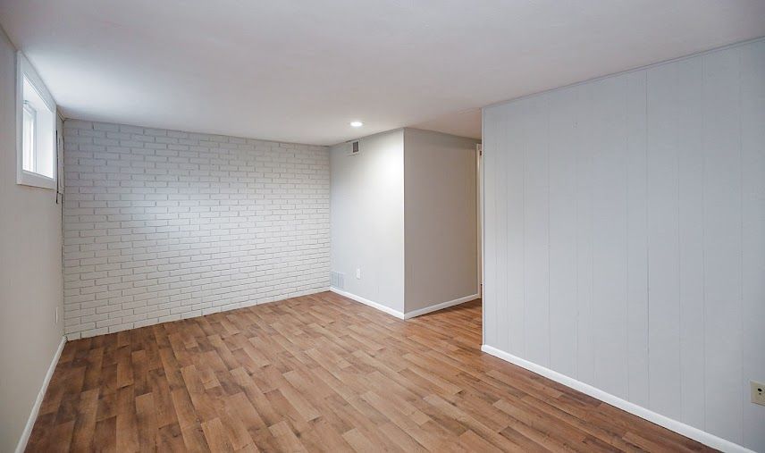 An empty room with hardwood floors and white walls.