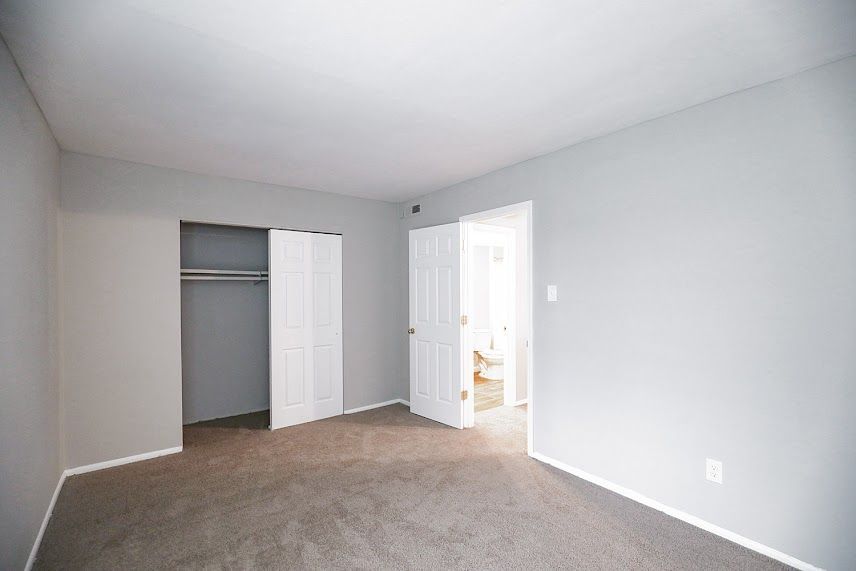An empty bedroom with a closet and a brown carpet.