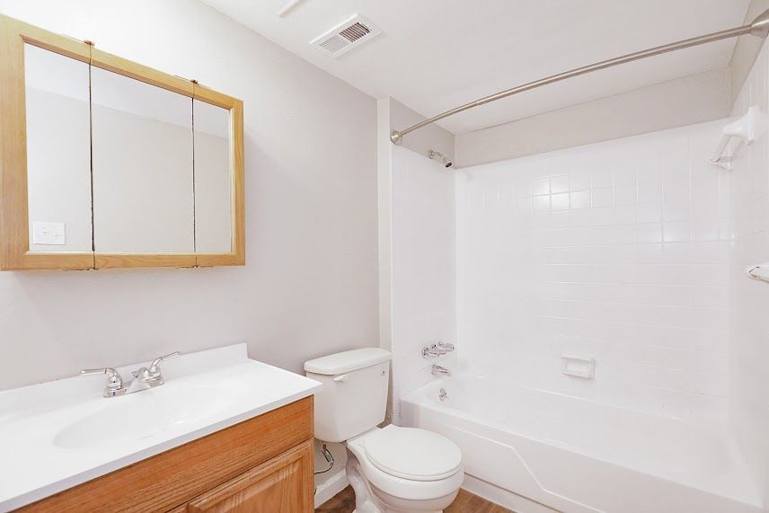 A bathroom with a toilet , sink , and bathtub.