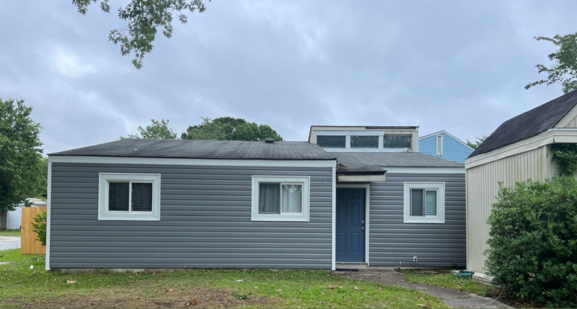 A man is standing on a ladder in front of a house.