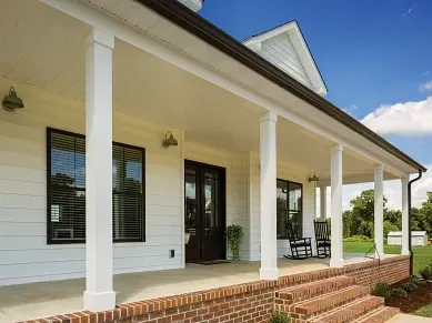 A white house with a large porch and brick steps.