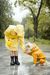 A woman and a dog wearing yellow raincoats are playing in the rain.