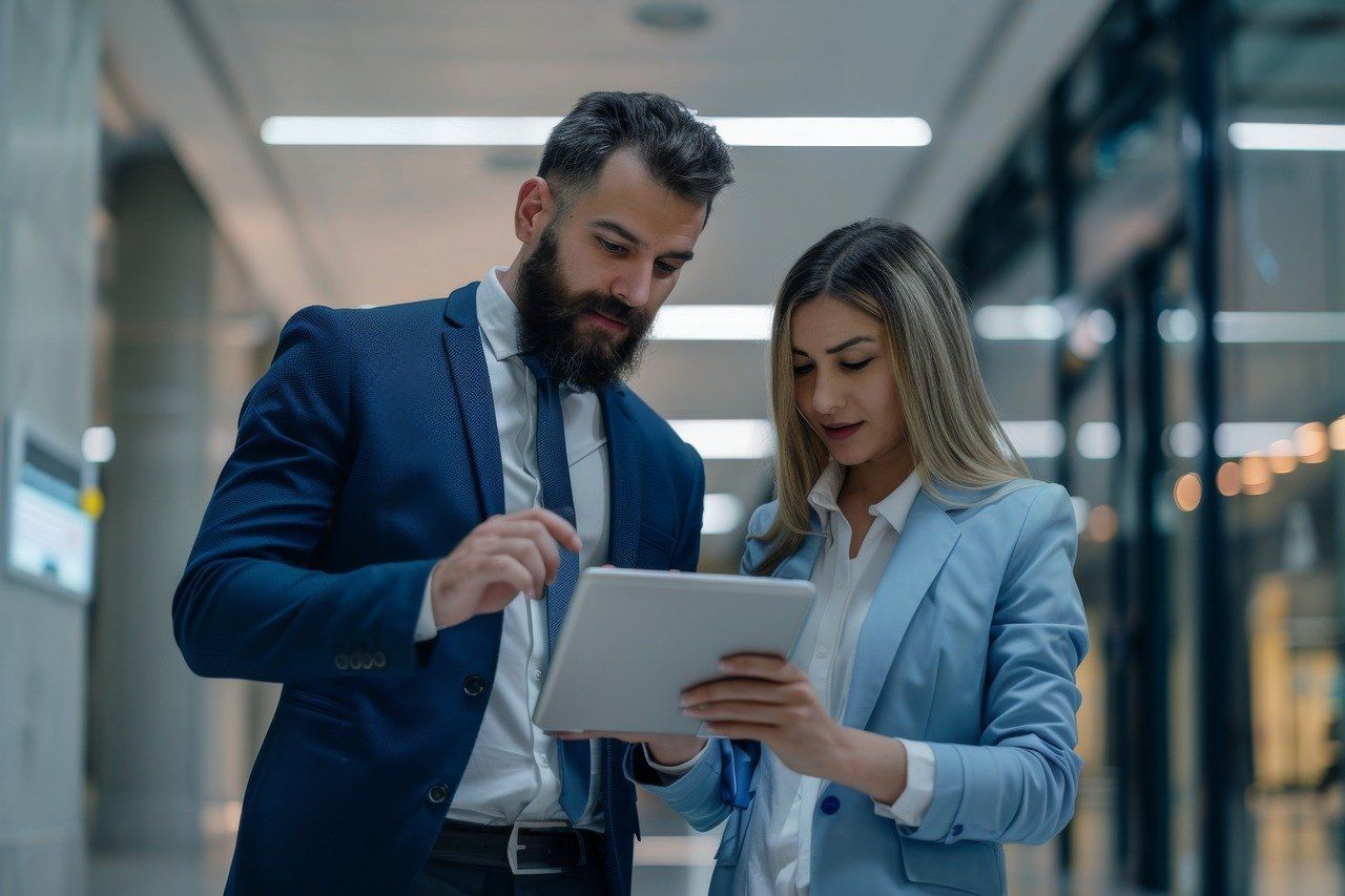 A man and a woman are looking at an automation on a tablet in a hallway.