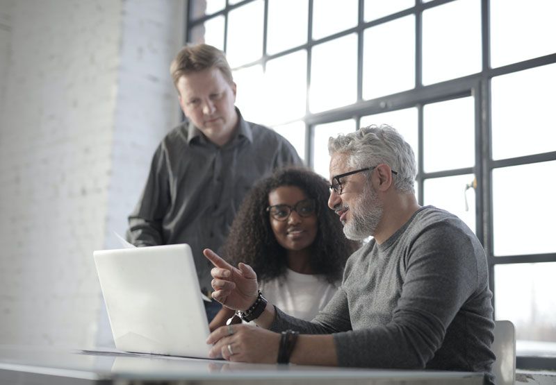 A group of people are looking at a laptop computer.