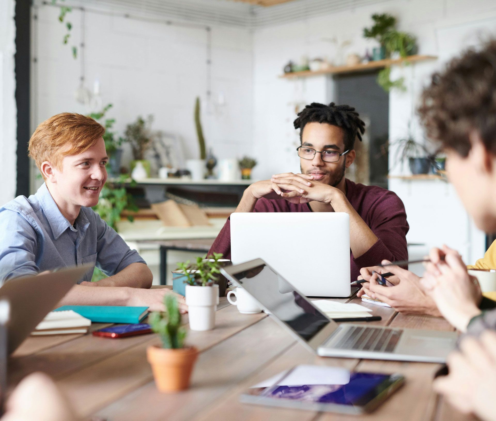 A group of people are sitting around a table with laptops.