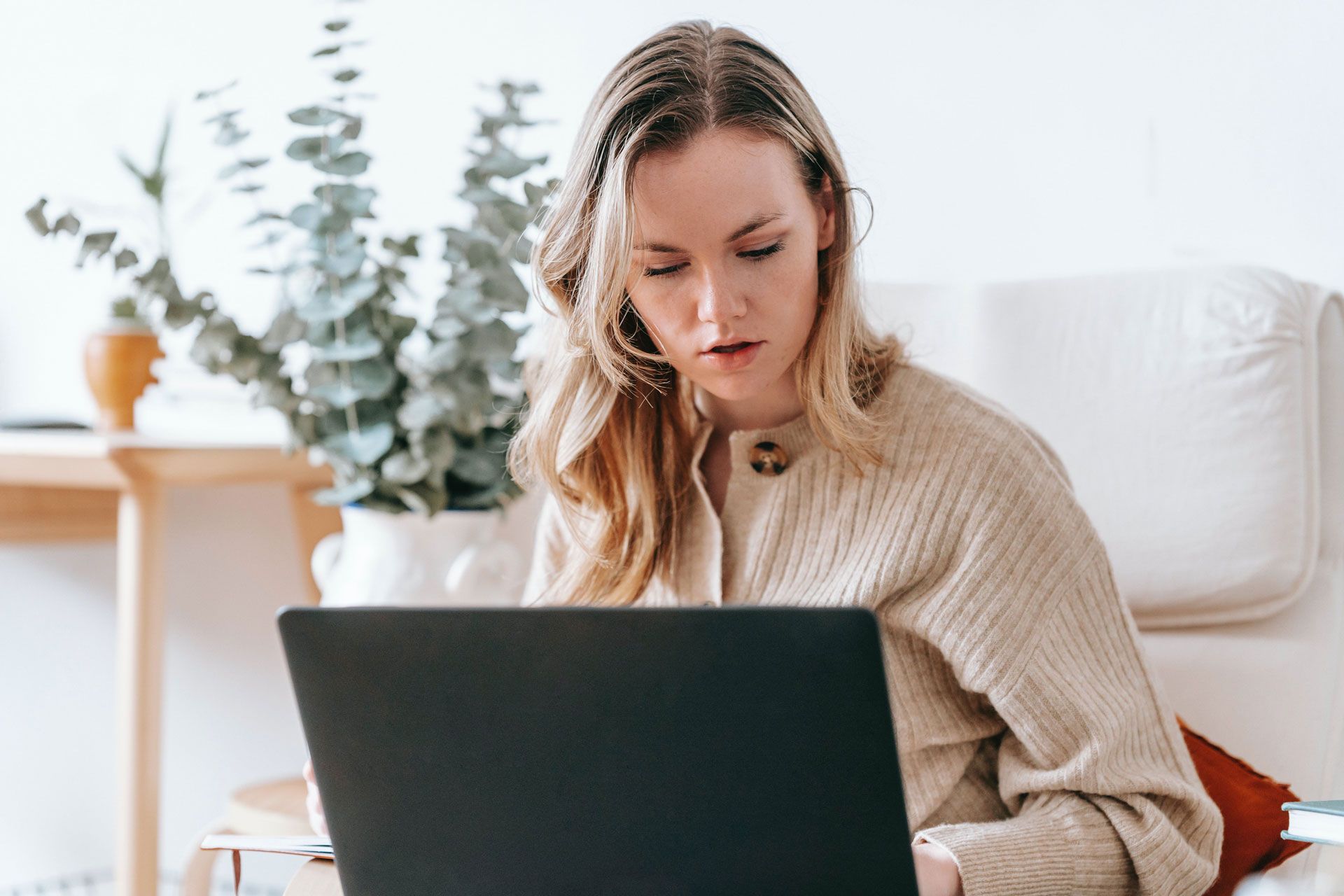 A woman is sitting in a chair using a laptop computer.