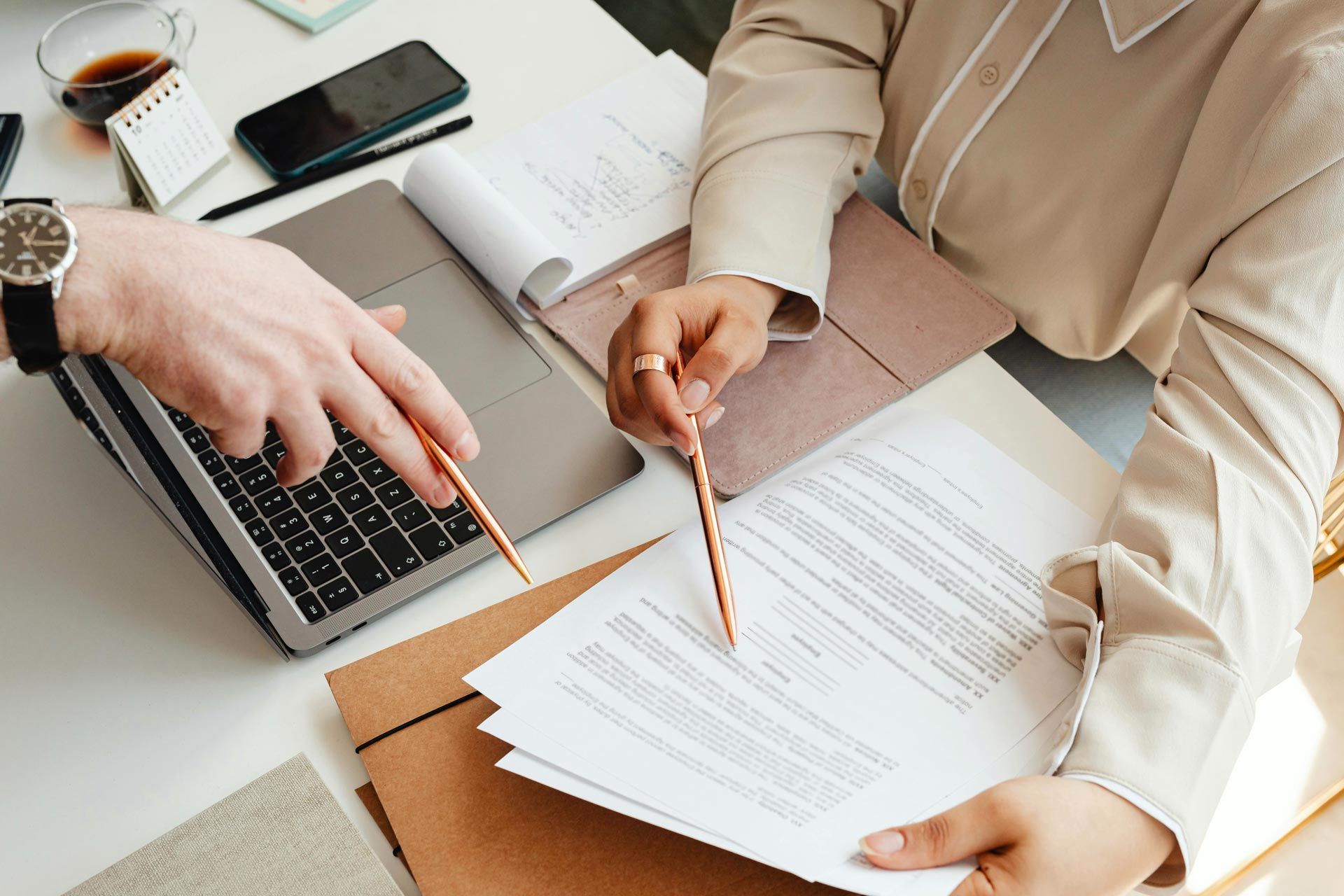 A man and a woman are sitting at a table with papers and a laptop.