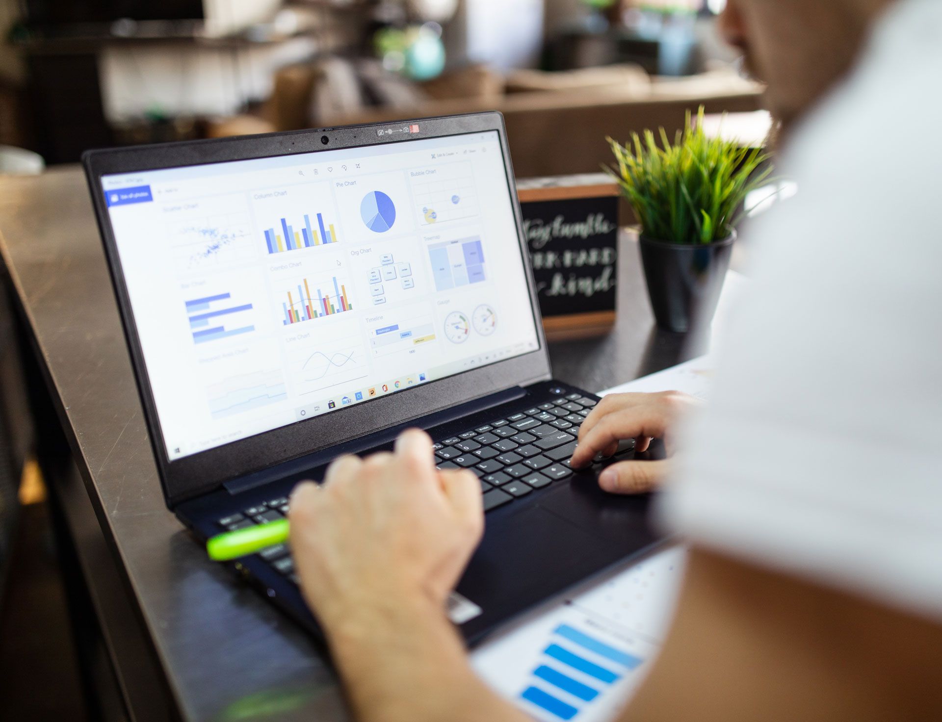 A man is using a laptop computer with a graph on the screen.