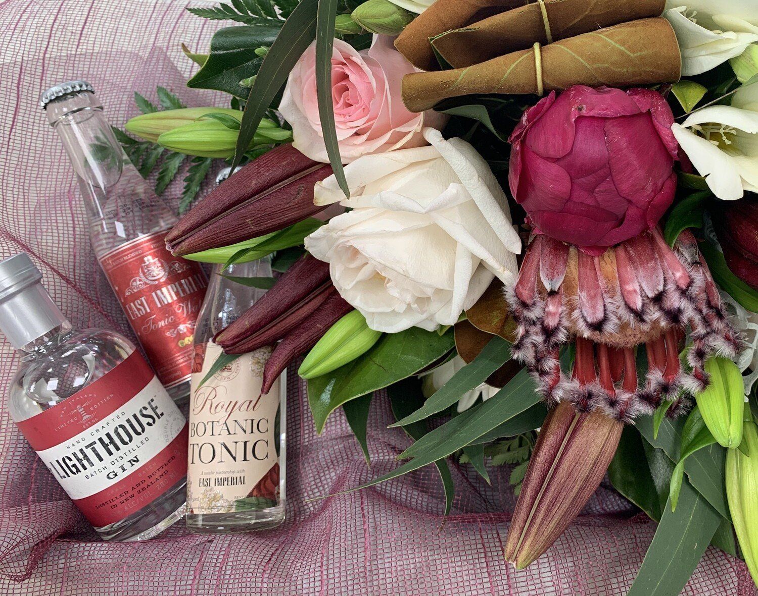 a bouquet of flowers next to a bottle of lighthouse tonic .