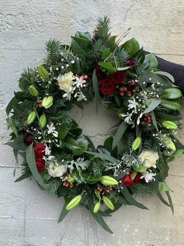 a christmas wreath with red roses and white flowers