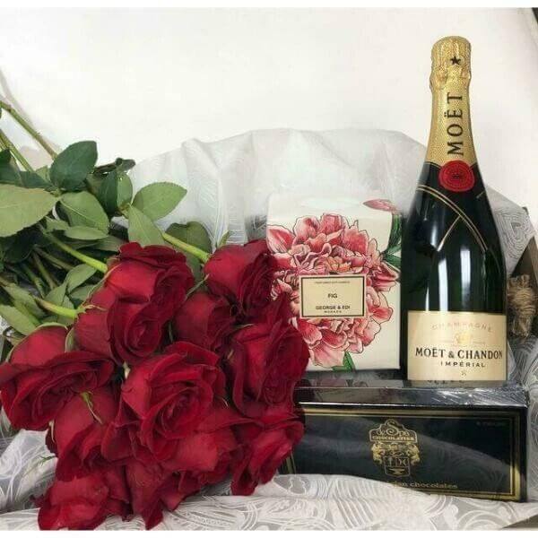 a bottle of moet next to a bunch of red roses