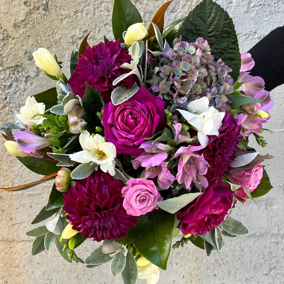 a person is holding a bouquet of purple and pink flowers