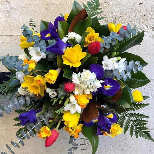 a bouquet of yellow and purple flowers with green leaves