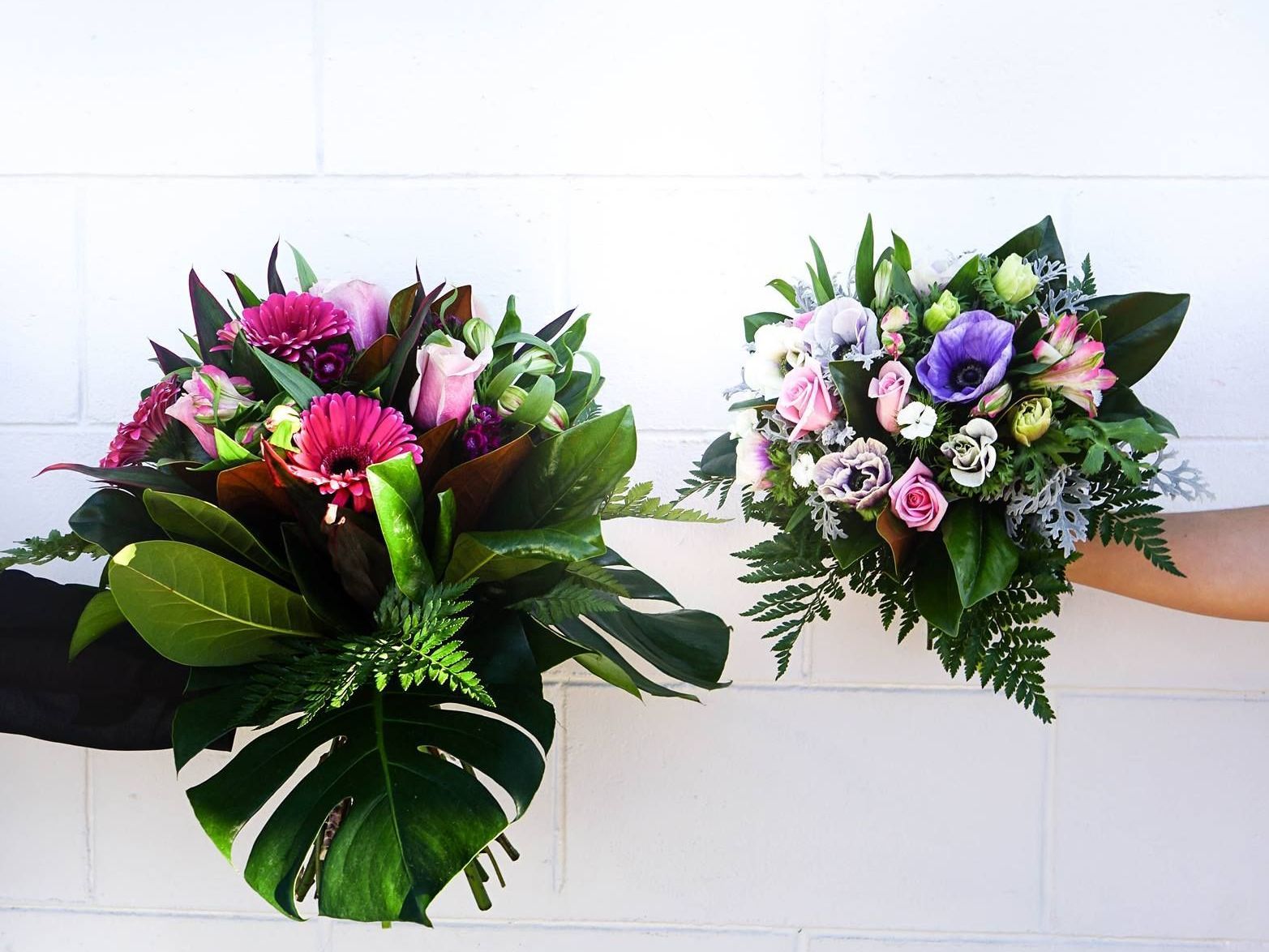 a person is holding two bouquets of flowers in their hands .