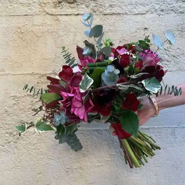 a person is holding a bouquet of flowers in front of a wall