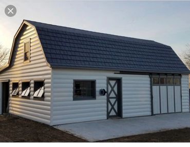 White barn with a gray roof and trim, several windows, and a concrete floor