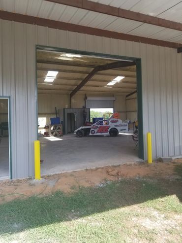 Race car inside a large shop with open door