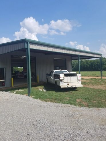 White pickup truck backed into garage under a green-trimmed awning