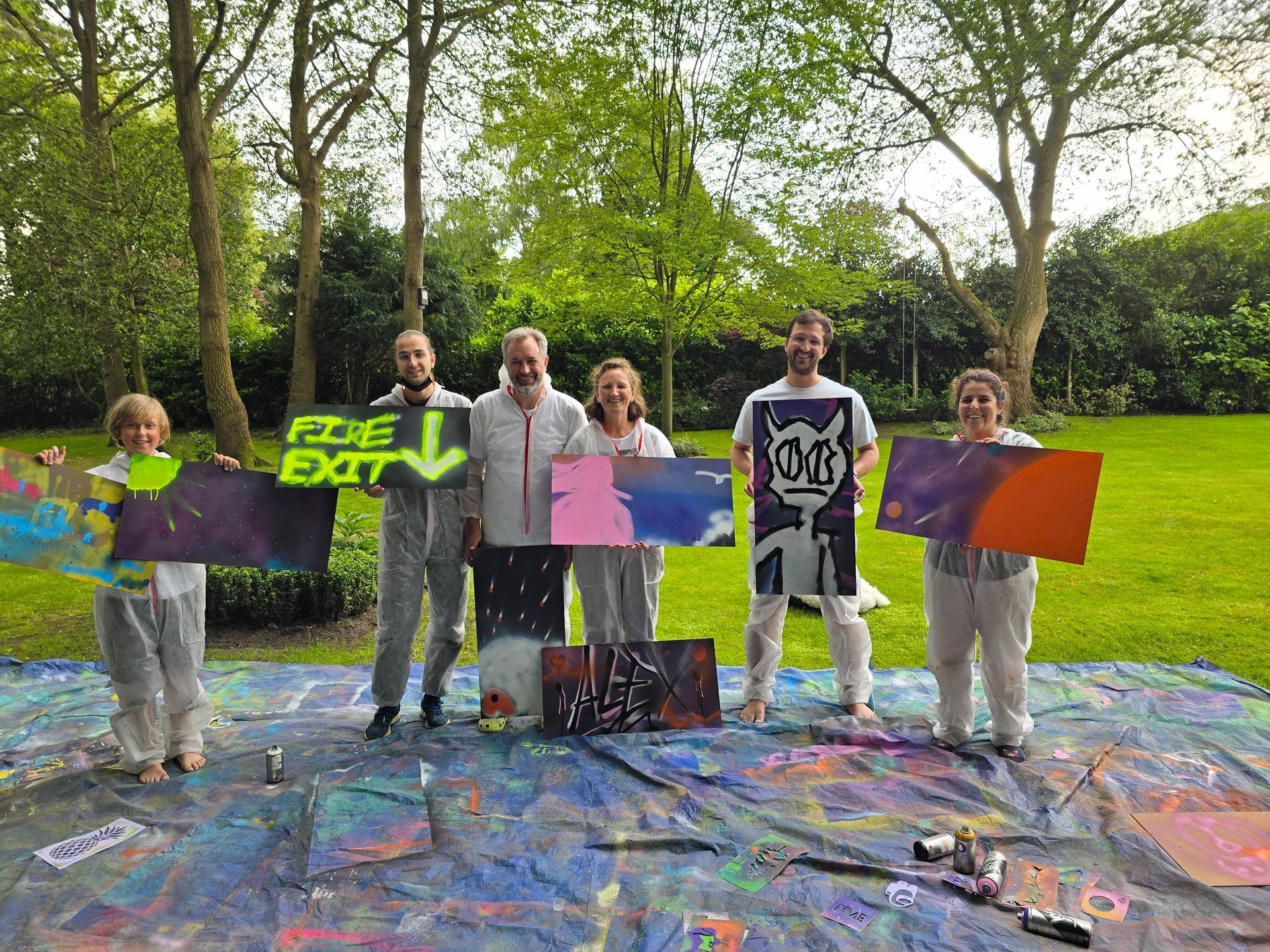 Family-friendly graffiti birthday party with parents and children holding their finished graffiti boards at a Street Stars home party.