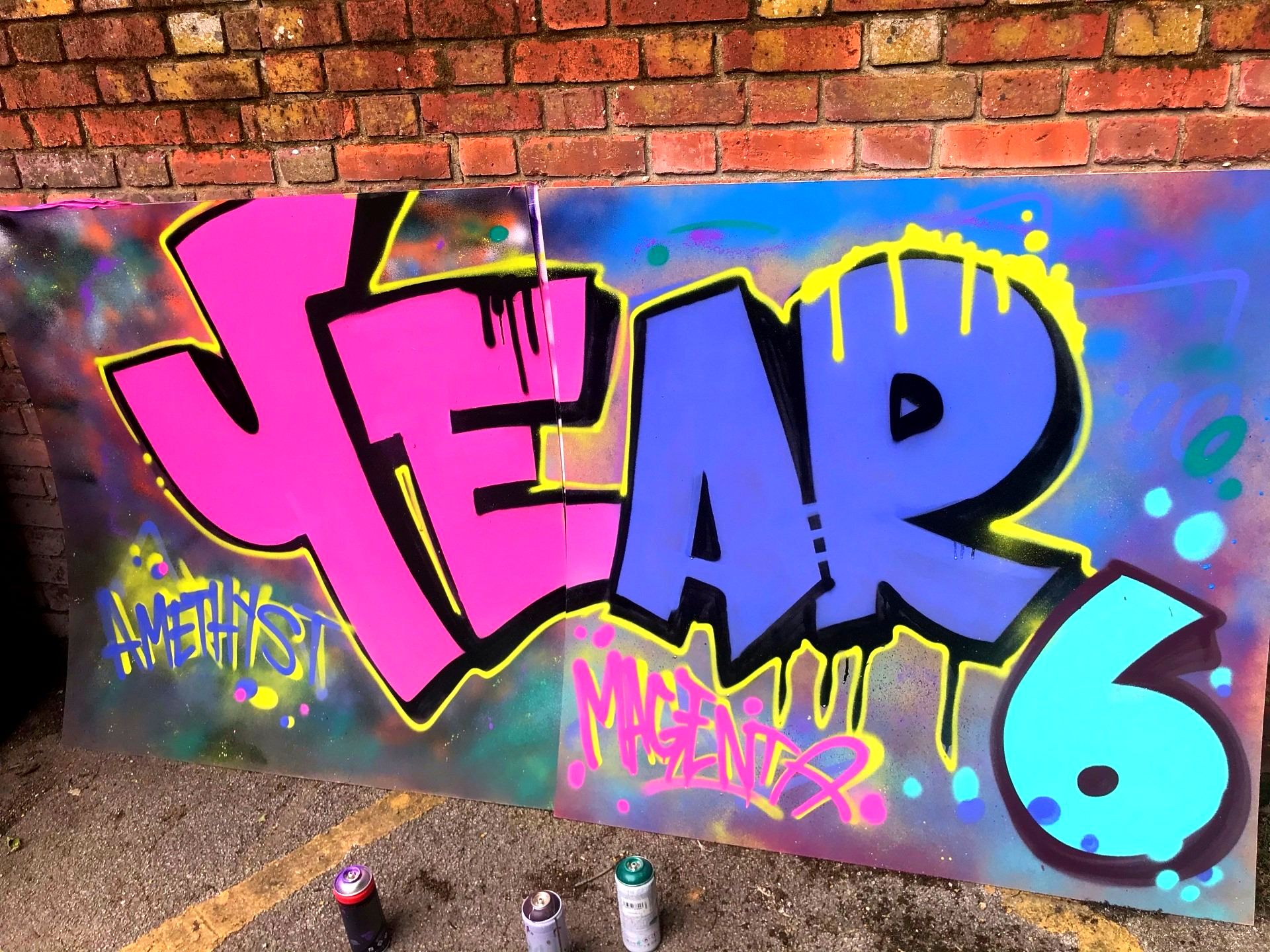 Collaborative graffiti mural board painted by year 6 pupils during a structured street art workshop led by professional graffiti artists