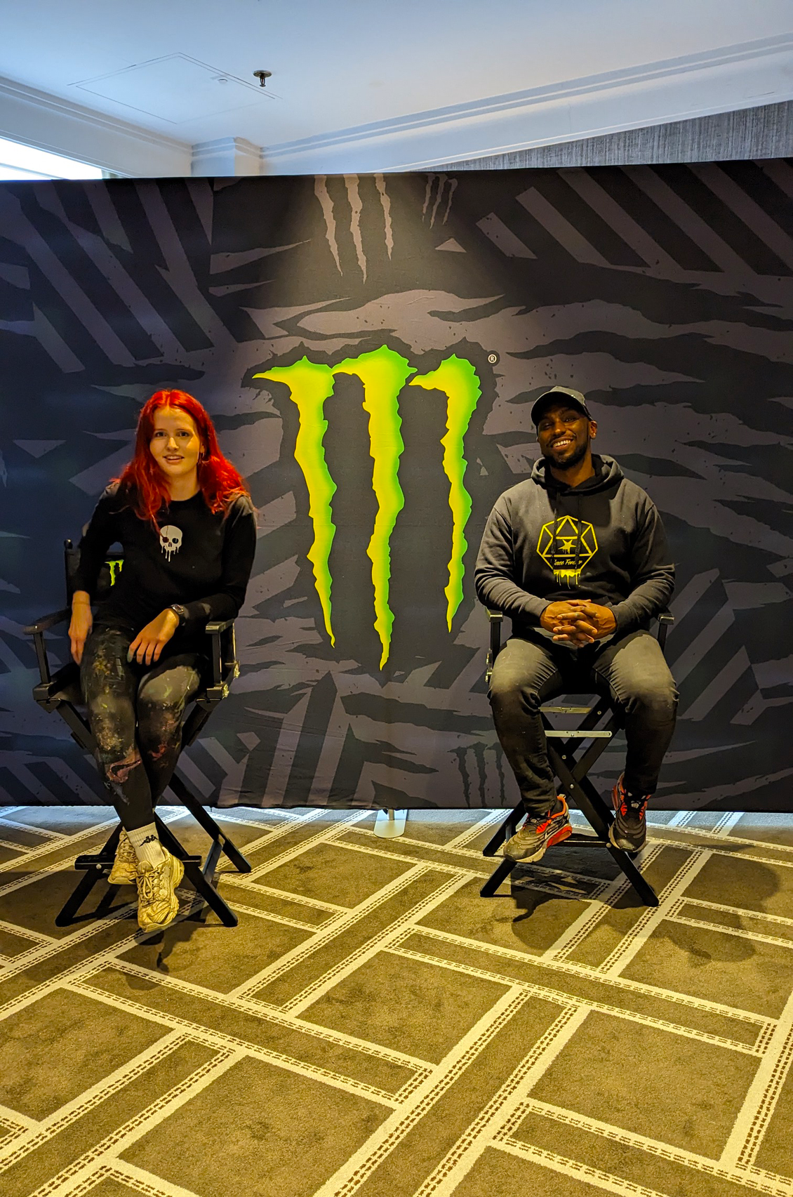 2 graffiti artists sitting in front of Monster Energy sign