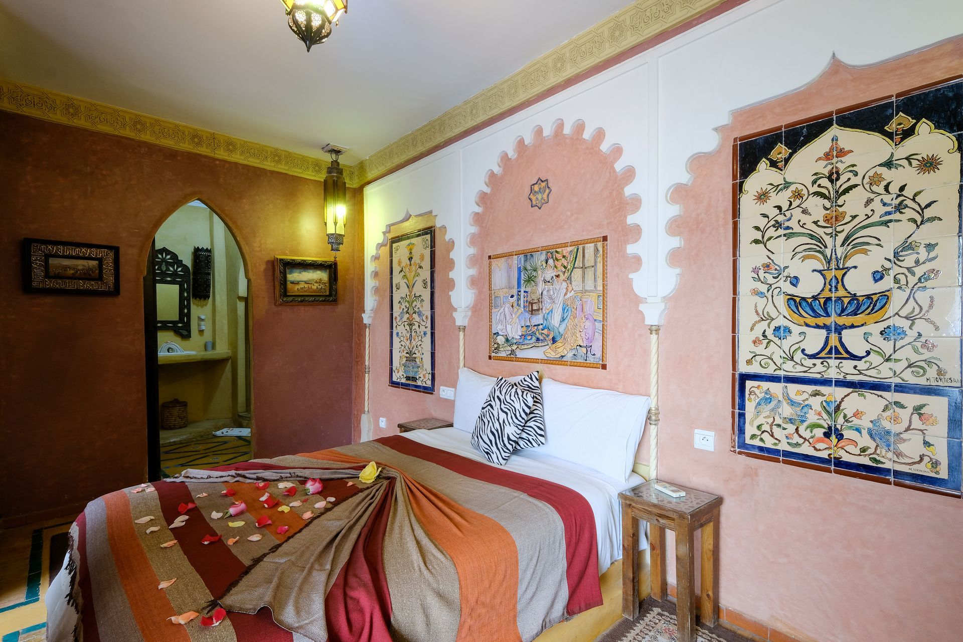 Bedroom with Middle Eastern decor; bed with decorative throw, arched doorways, tiled wall art.