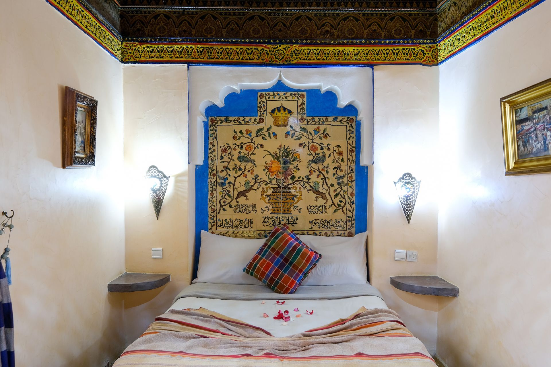 Bedroom with ornate, decorated ceiling, blue arched headboard, rug, and bed.
