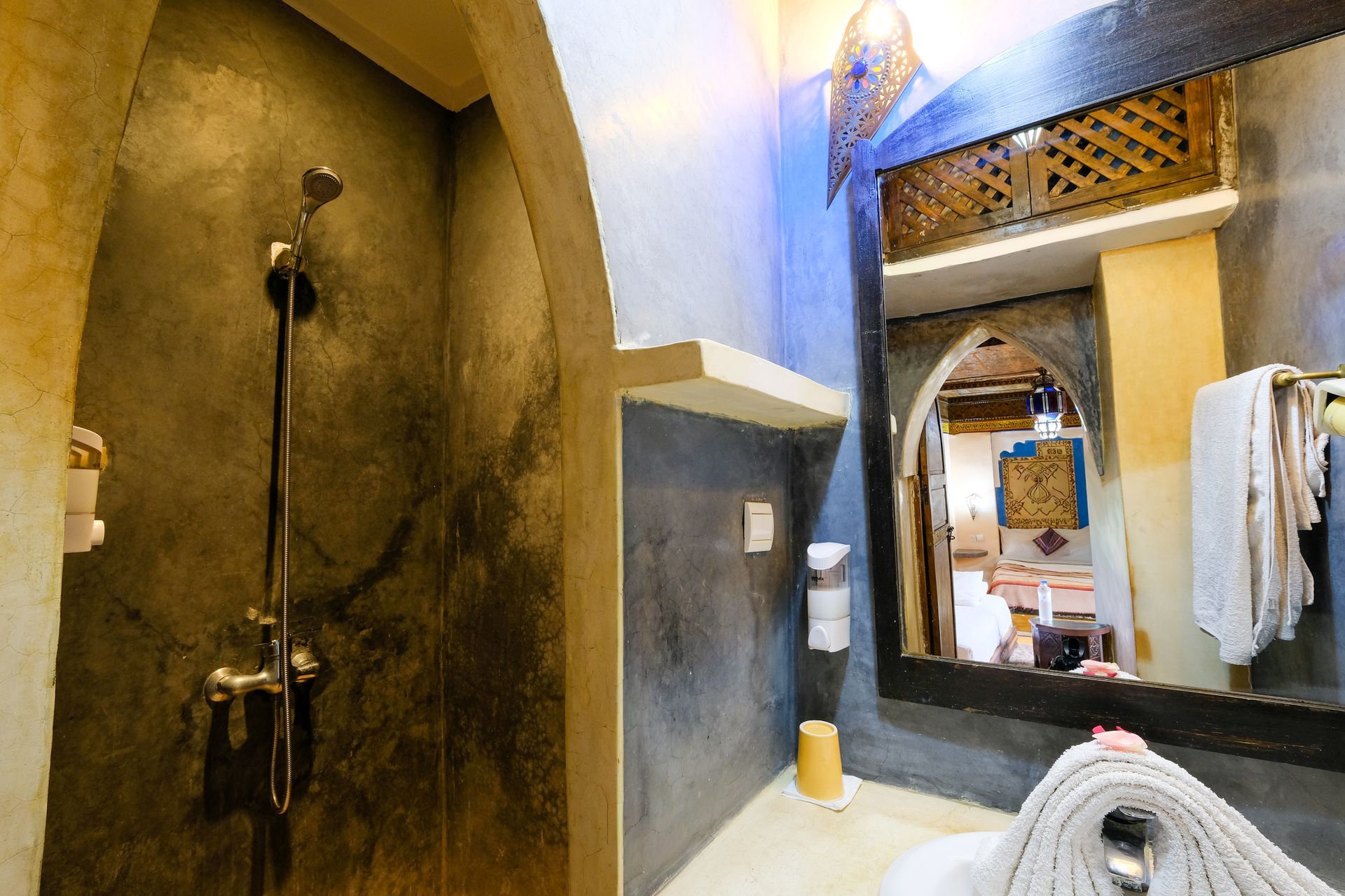 Shower stall with gray concrete walls, arched doorway, and large mirror.