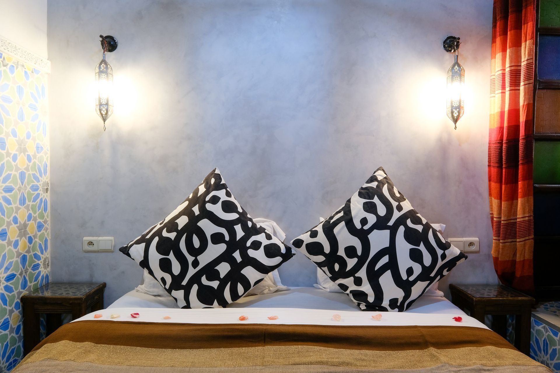 Bedroom with bed, decorative pillows, wall sconces, and colorful accents.