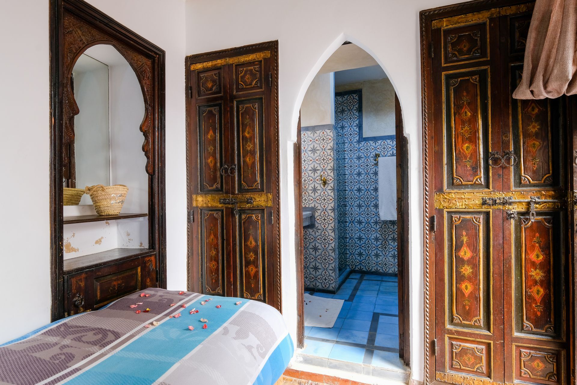 Bedroom interior with ornate wooden doors, archways, and a tiled shower visible.