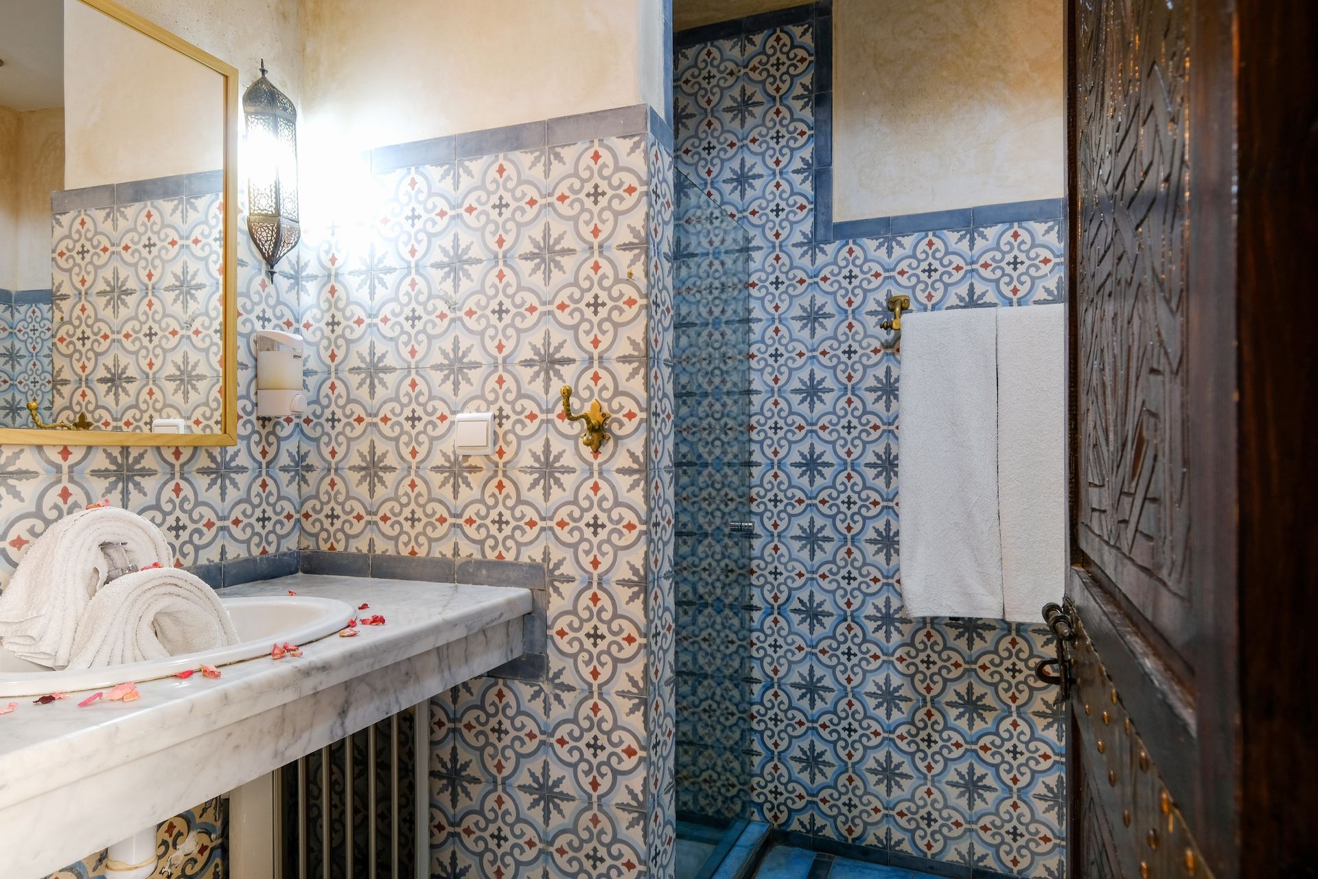 Bathroom with patterned tile walls, marble countertop, and open wooden door.
