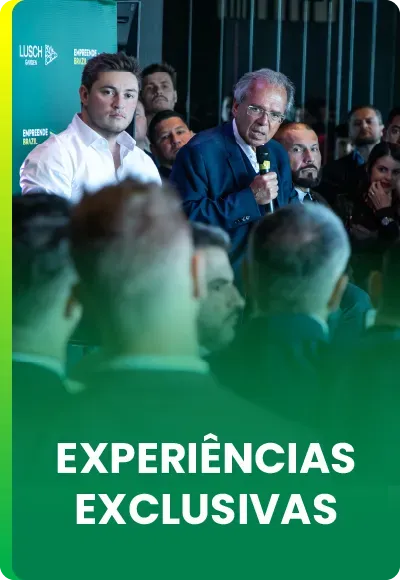 Um homem fala ao microfone em um evento com uma plateia em primeiro plano. O texto abaixo diz: 